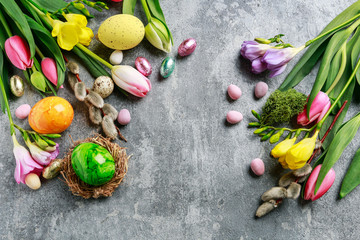 Colorful flowers and painted Easter eggs on grey, stone background