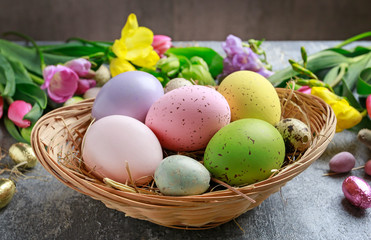 Colorful flowers and painted Easter eggs on grey, stone background