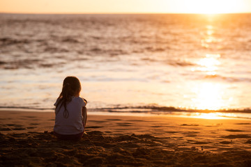 Fototapeta premium Isolated girl child facing towards sea during sundown
