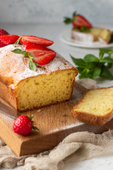 Pound or loaf cake with strawberry and mint on wooden board. Delicious summer dessert.