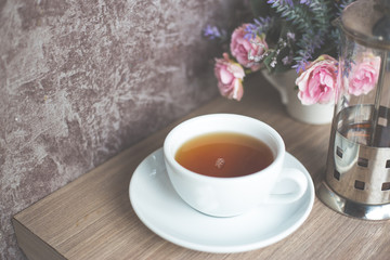 A cup of green tea on wooden table. Beverage for healthy with rose flower in pot