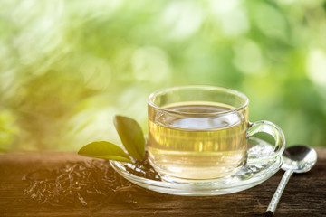 A cup of green tea on wooden table with leaf and natural background, beverage for relaxation.