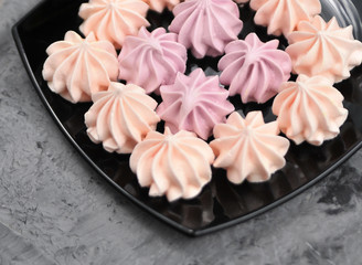 Meringues in plate on stone background.