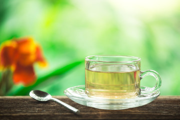 A cup of green tea on wooden table with leaf and natural background, beverage for relaxation.