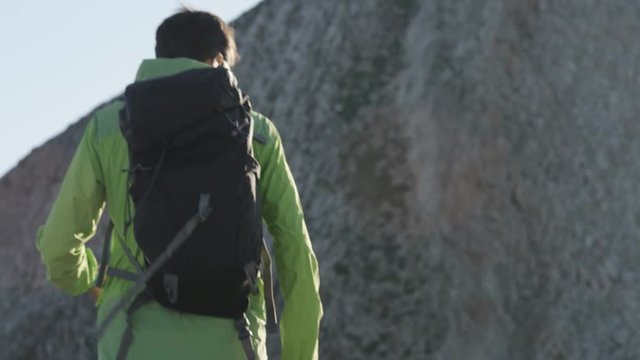 Man takes off backpack and rests on rock while hiking