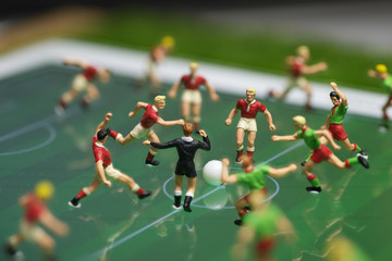 Side view of miniature toys figurines football (soccer) players on a computer electronic pad.