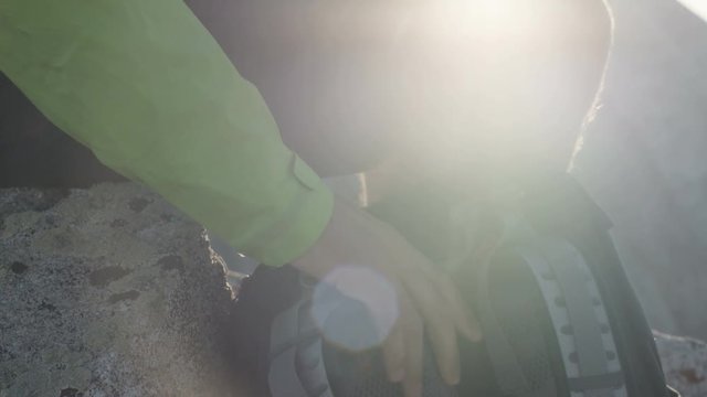 Close up of man's hands as he grabs backpack and puts it on while he is hiking