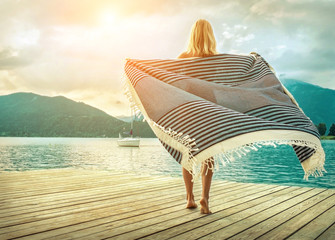 Obraz premium Happiness blonde woman stay on the wooden pier near the mountain