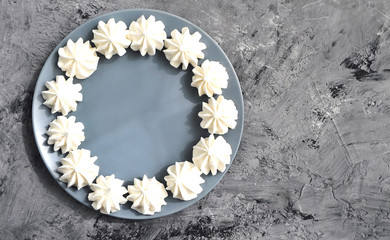 Meringues in plate on stone background.