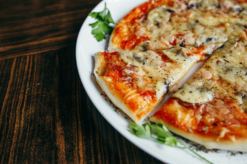 Hot pizza slice with melting cheese on a wooden table.