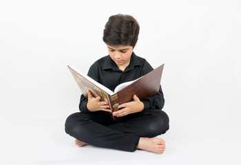 Muslim young boy reading Quran, the holy book of Islam
