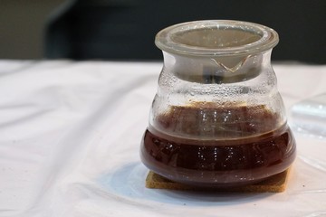 Close up a glass of hot drip coffee on white dinning table background 