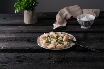 homemade dumplings, on a rustic plate on an old wooden backdrop, dark background