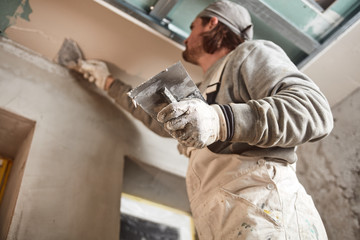 Workman plastering gypsum walls inside the house.