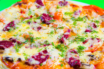 Obraz na płótnie Canvas hot tasty fresh pizza on a plate close-up. green background