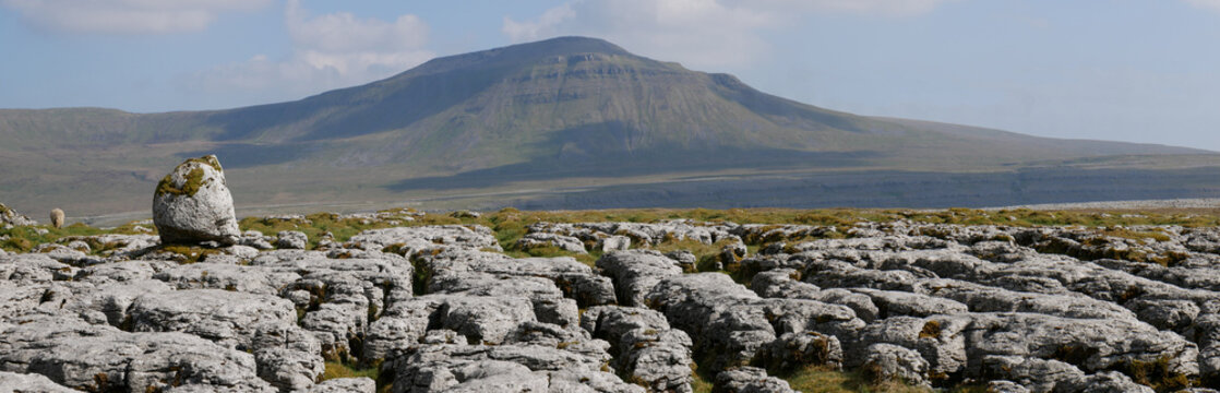 Limestone pavement - an area of limestone eroded by water - on Scales Moor in the Yorkshire Dales, UK, with Ingleborough in the background