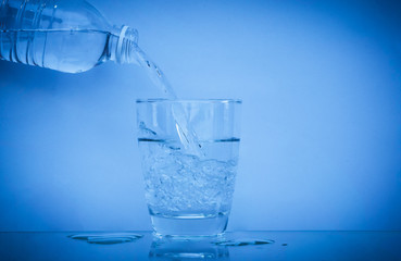 Close up water splashing pouring purified fresh drink water from the bottle with background