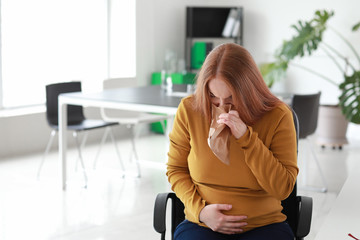 Young pregnant woman suffering from toxicosis in office