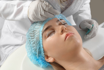 Young woman undergoing procedure of eyelashes lamination in beauty salon