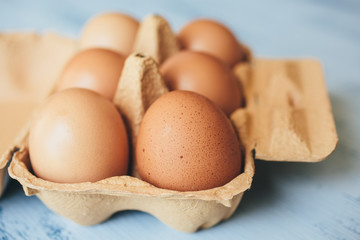 Eggs background. Closeup view of eggs in carton box on wooden table. 