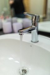 Modern faucet of chrome color in bathroom interior at home