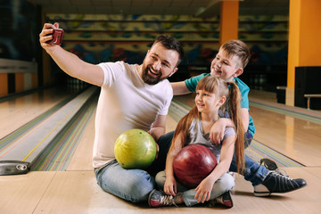 Fototapeta premium Man and his children taking selfie in bowling club