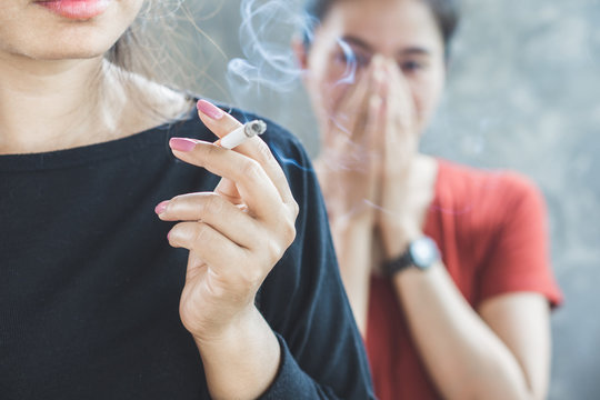 Asian woman smoking cigarette near people in family smelling pollution,passive smoking concept