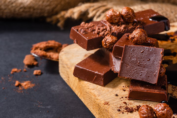 Close-up of dark chocolate bars and other products on wooden cutting board