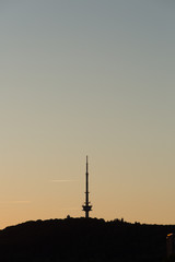 Fernseher Turm an H&uuml;gel im Schatten vor untergegender Sonne