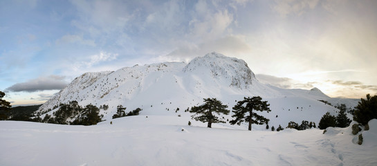 Panorama of snowy mountain landscape with cloudy sky.
