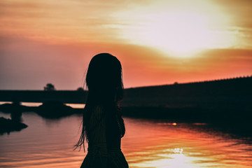 a beautiful girl standing in front of calm water and beautiful sunset sky at nyari dam, rajkot, India. 