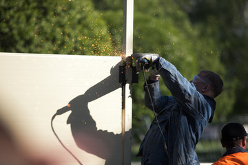 A construction worker using an angle grinder producing a lot of sparks