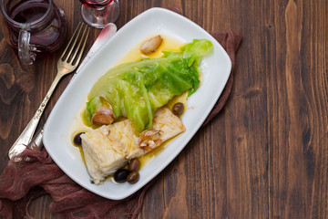 boiled cod fish with olive oil and vegetables on white plate