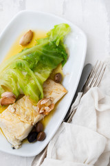 boiled cod fish with olive oil and vegetables on white plate