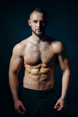 Fototapeta premium Low key portrait of muscular shirtless man at dark background