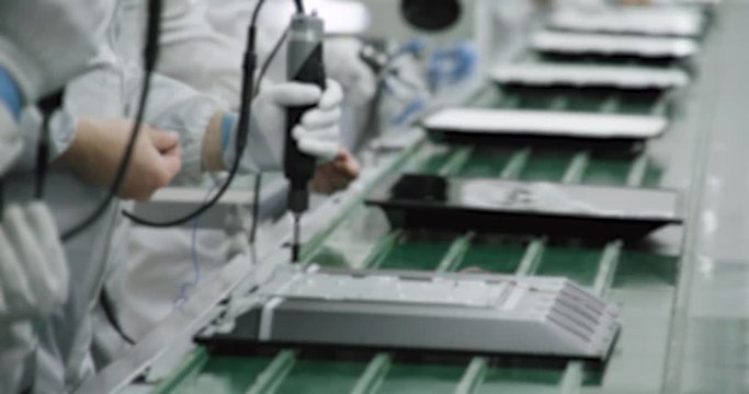 Blurred view of Innovative production of TVs, view of the assembly line, workers in white, the process of assembling TVs on the conveyor, slow motion.