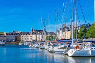 Vannes harbor, in the Morbihan, Brittany, boats in the marina, with typical houses and the cathedral in background  - obrazy, fototapety, plakaty