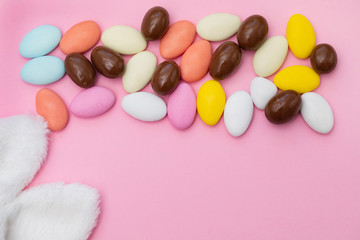 close up of chocolate egg and candy drops on pink background
