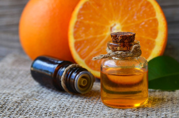 Orange essential oil in a glass bottle and fresh fruits on old wooden table.Citrus oil for skin care, spa, wellness, massage, aromatherapy and natural medicine.Selective focus.Copy space.