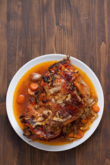 baked turkey leg with vegetables and herbs on white dish