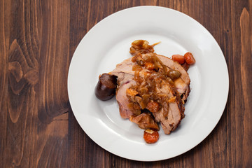 baked turkey leg with vegetables, smoked sausage and herbs on white dish