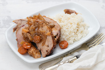 baked turkey leg with vegetables, smoked sausage, herbs and boiled rice on white dish