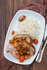 baked turkey leg with vegetables, smoked sausage, herbs and boiled rice on white dish