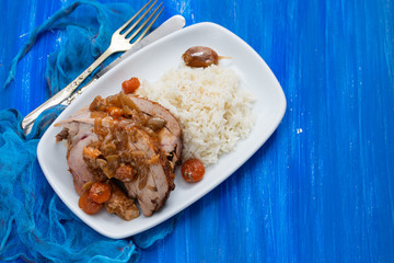 baked turkey leg with vegetables, smoked sausage, herbs and boiled rice on white dish