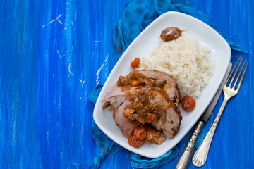 baked turkey leg with vegetables, smoked sausage, herbs and boiled rice on white dish