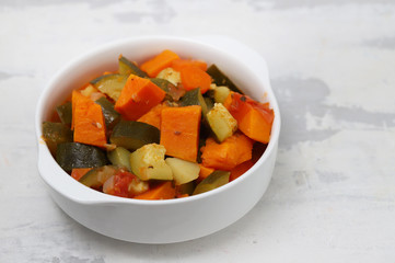 boiled vegetables in white bowl on ceramic background