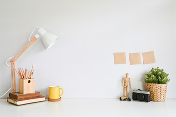 Creative table with camera, wooden model, lamp, books and coffee with sticky note, Workspace concept.