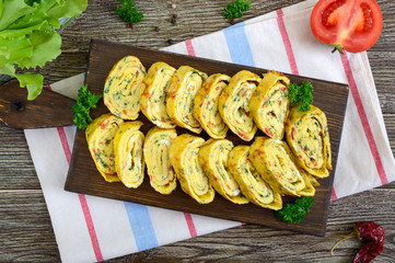 Omelette, egg roll with vegetables and herbs on a wooden table. Delicious healthy breakfast. Top view.