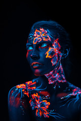 Beautiful flowers in UV light on a young girl face and body