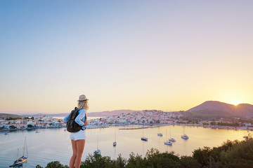 Fototapeta na wymiar Enjoying vacation in Greece. Young traveling woman enjoying sunset on sea view point.